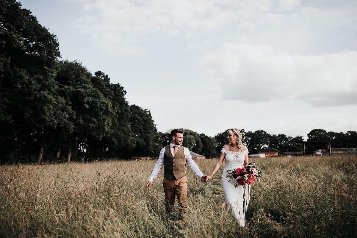 Bride & Groom strolling through the crop field on a farm on their wedding day